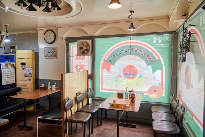The dining area inside Sky Pizza in Noryangjin, with its Parasite photo-zone window.